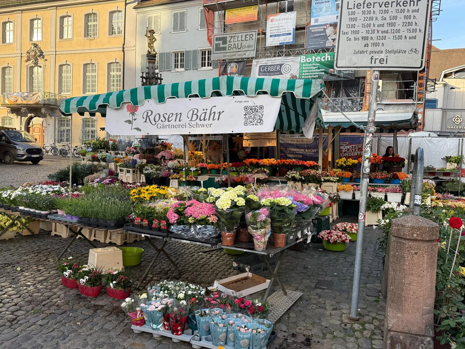 Rosen-Bähr-Blumenstand mit grün-weiß gestreifter Markise und Blumen auf dem Freiburger Münstermarkt