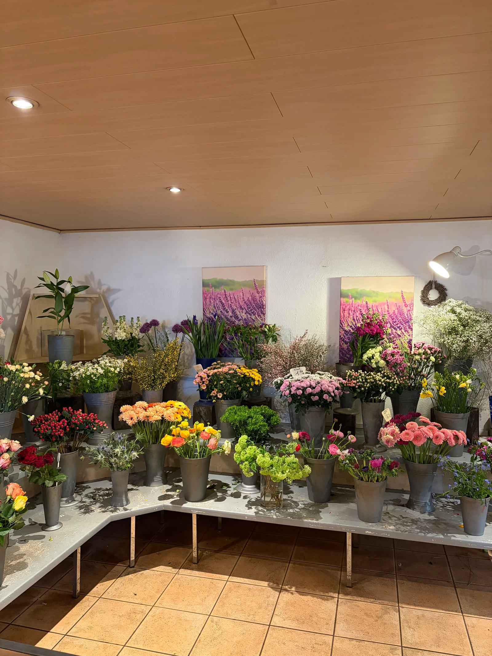 Bunte Schnittblumen in grauen Vasen auf gestuften Tischen im Blumenladen in Friesenheim