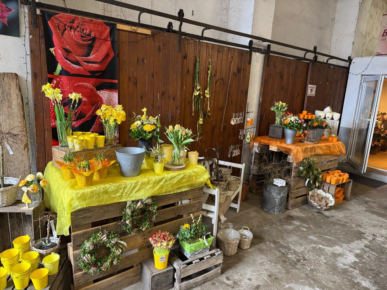 Blumen und Pflanzgefäße vor großen Holztoren im Scheunenladen von Rosen Bähr in Friesenheim