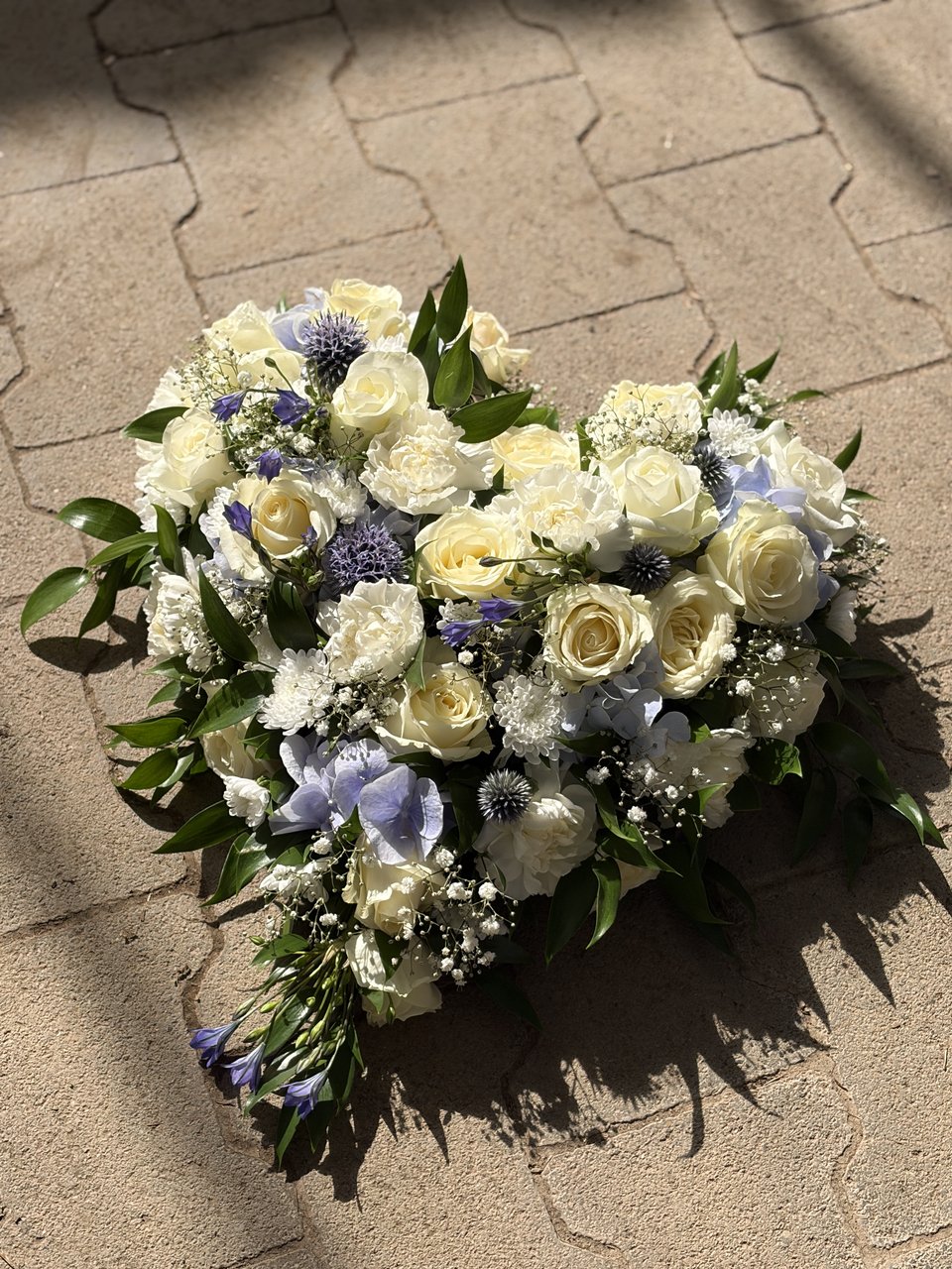 Weiß-blaues florales Gesteck für die Trauerfloristik