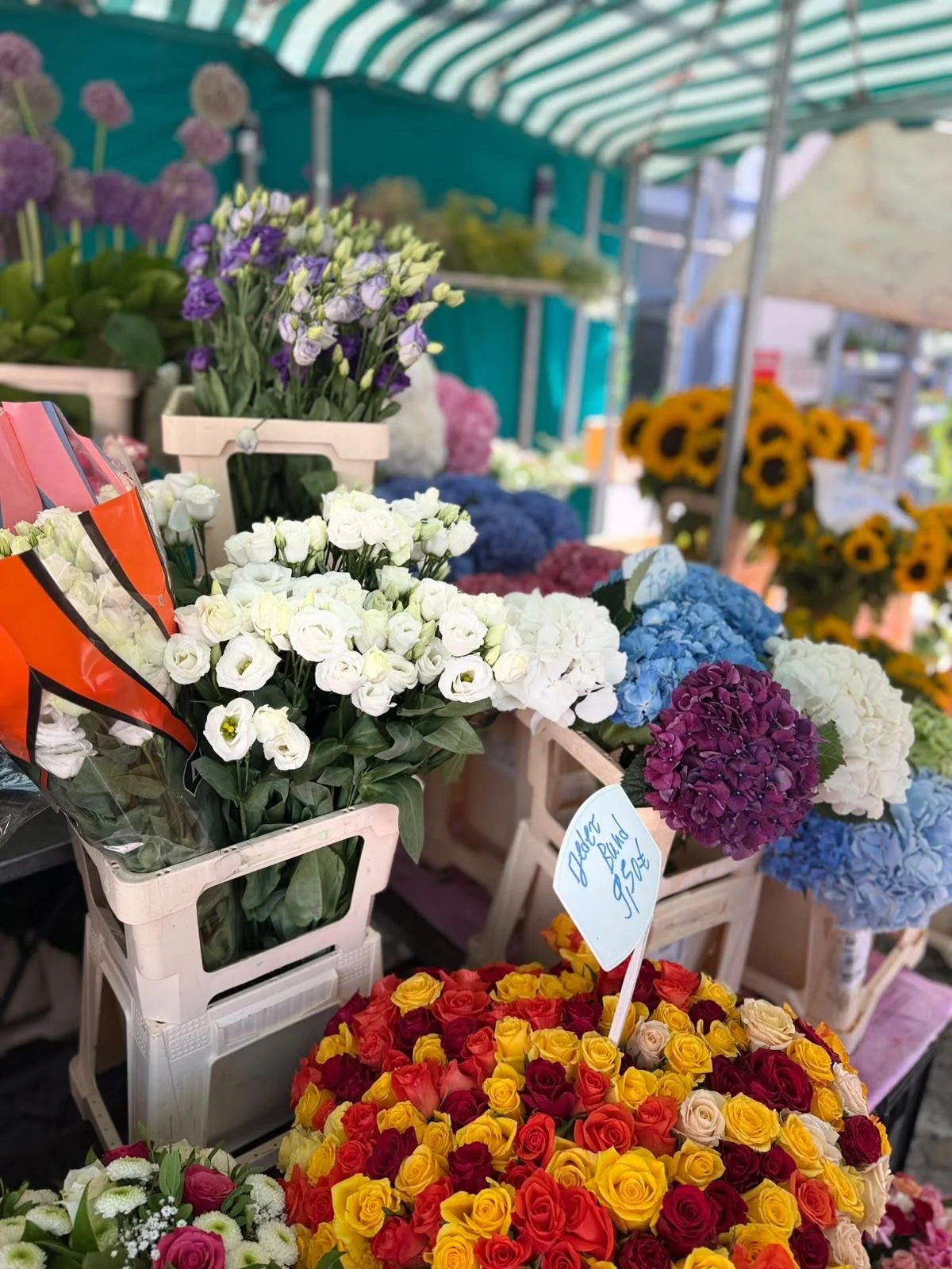 Blumenvielfalt am Marktstand unter einer gestreiften Markise